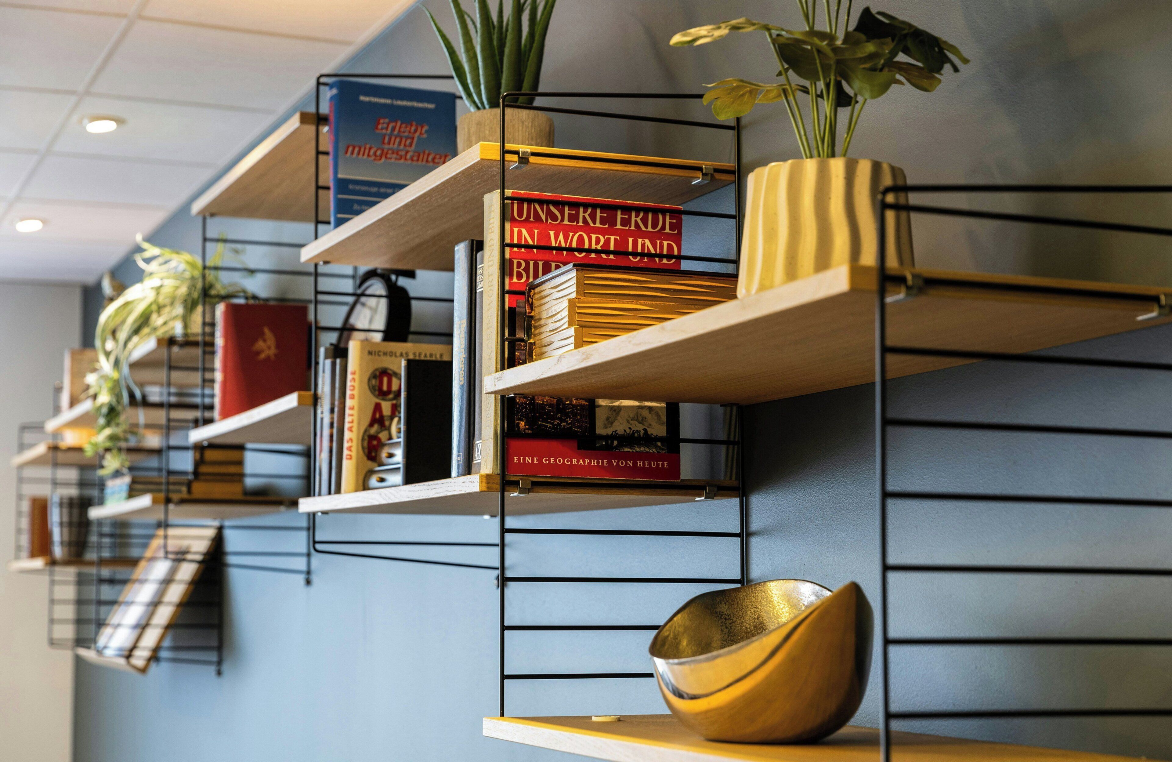 A wall with multiple shelves holding books, decorative items, and a bowl.