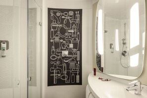Une salle de bain moderne avec un grand miroir, une douche et une œuvre d’art murale représentant des objets de salle de bain.