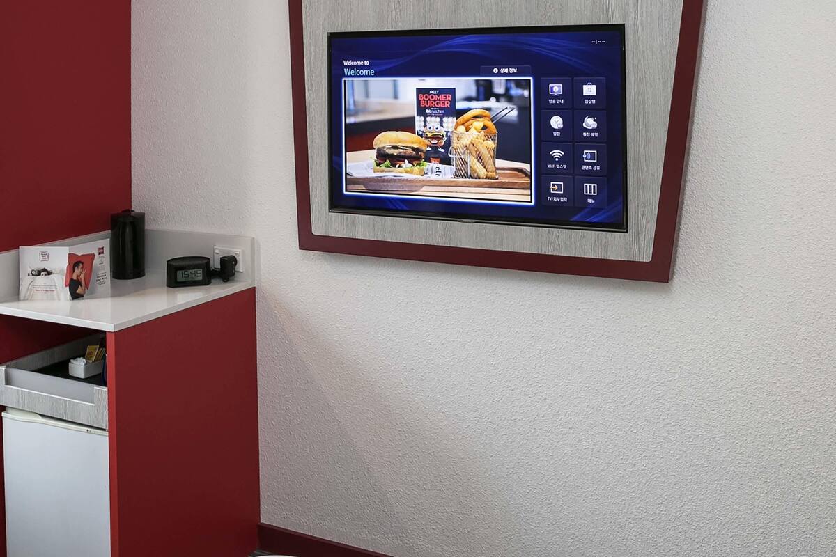 Een digitaal scherm waarop een restaurantmenu, een klok en een klein plankje met spullen staan.