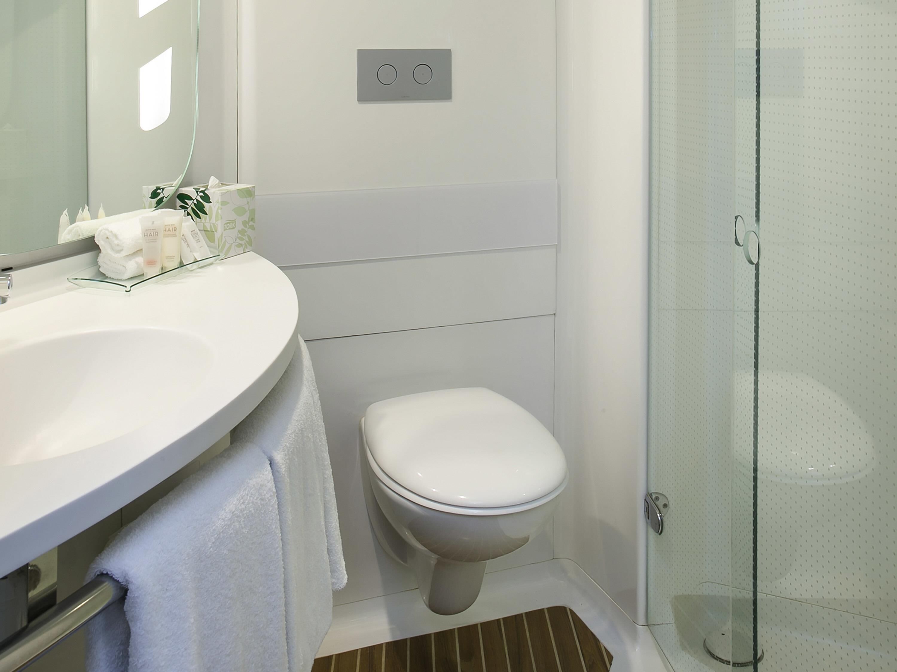 A bathroom with a white sink, toilet, and glass shower enclosure.