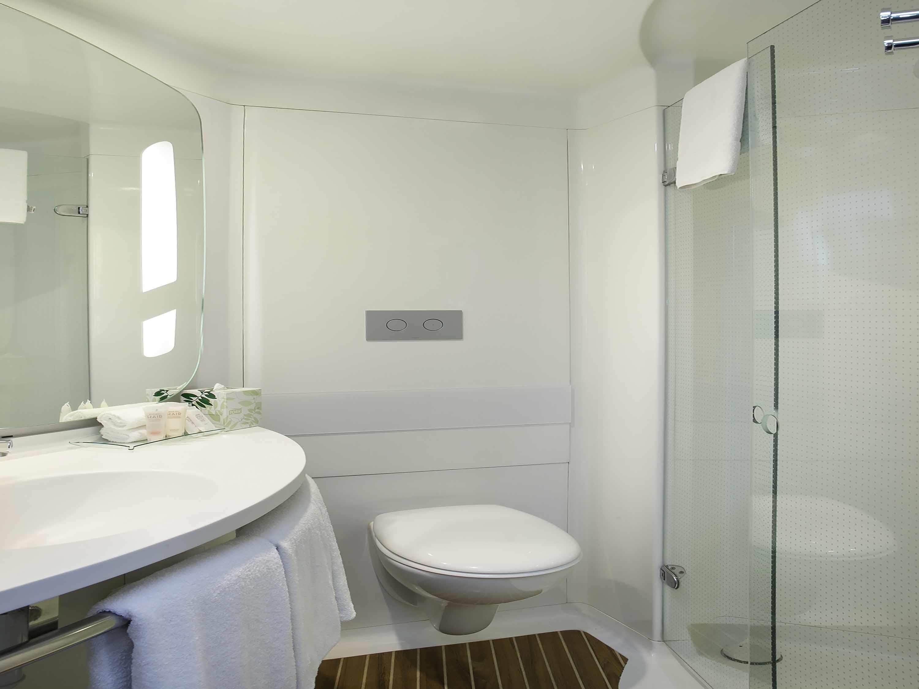 A modern bathroom with a white sink, toilet, and glass shower enclosure.