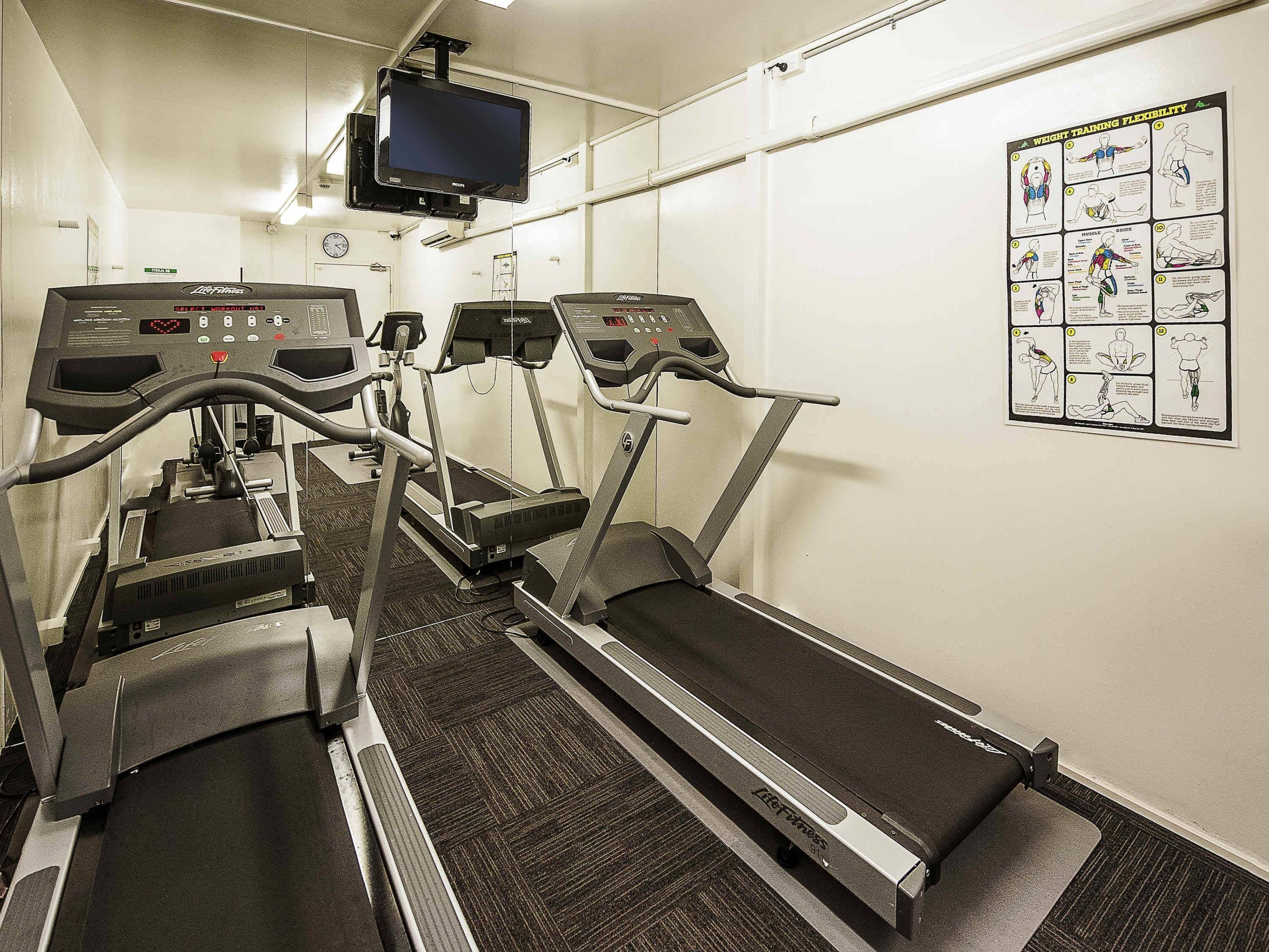 A gym with treadmills, a stationary bike, and a wall-mounted TV.