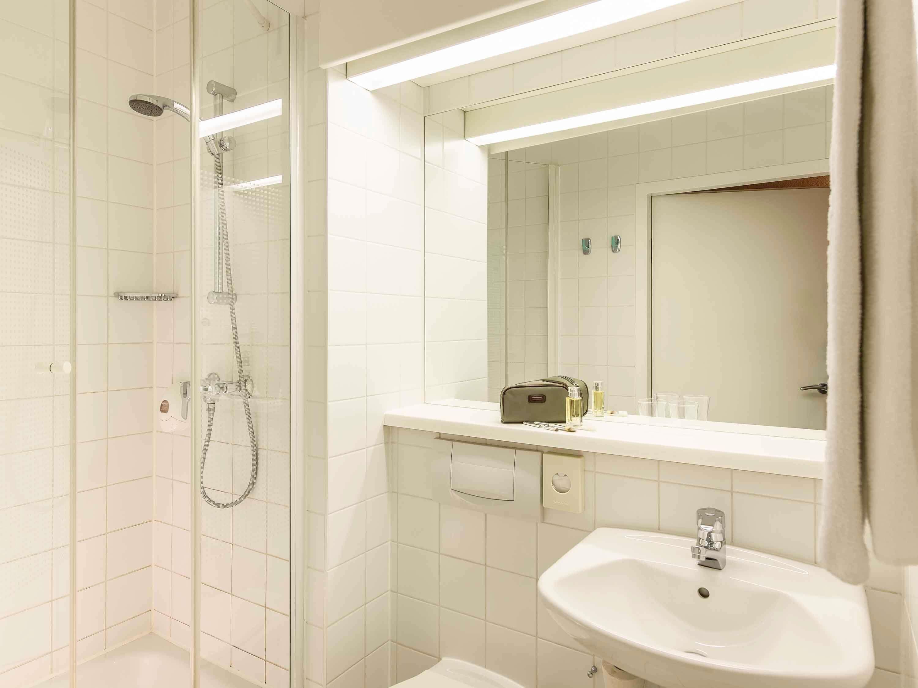 A bathroom with a glass-enclosed shower, a sink, and a mirror above it.