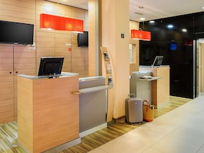 Ein Hotel-Empfangsbereich mit Holzvertäfelung, einem Samsung-Fernseher und einer roten Pendelleuchte.