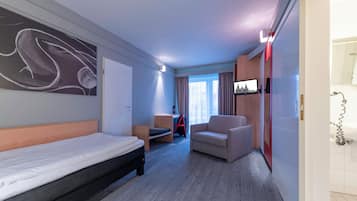 Une chambre d’hôtel avec un lit, un canapé, une chaise, une télévision et un bureau.