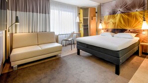 A hotel room with a bed, a sofa, a desk, and a chair. - ibis Luebeck (Lübeck)