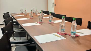 Ein Konferenzraum mit einem langen Tisch, Stühlen, Wasserflaschen und Notizblöcken.