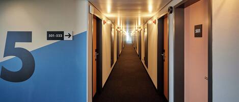 Un largo y estrecho pasillo con puertas a ambos lados, numeradas del 501 al 522, que conduce a habitaciones individuales.
