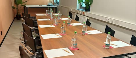 A conference room with a long table, chairs, water bottles, and a TV screen on the wall.