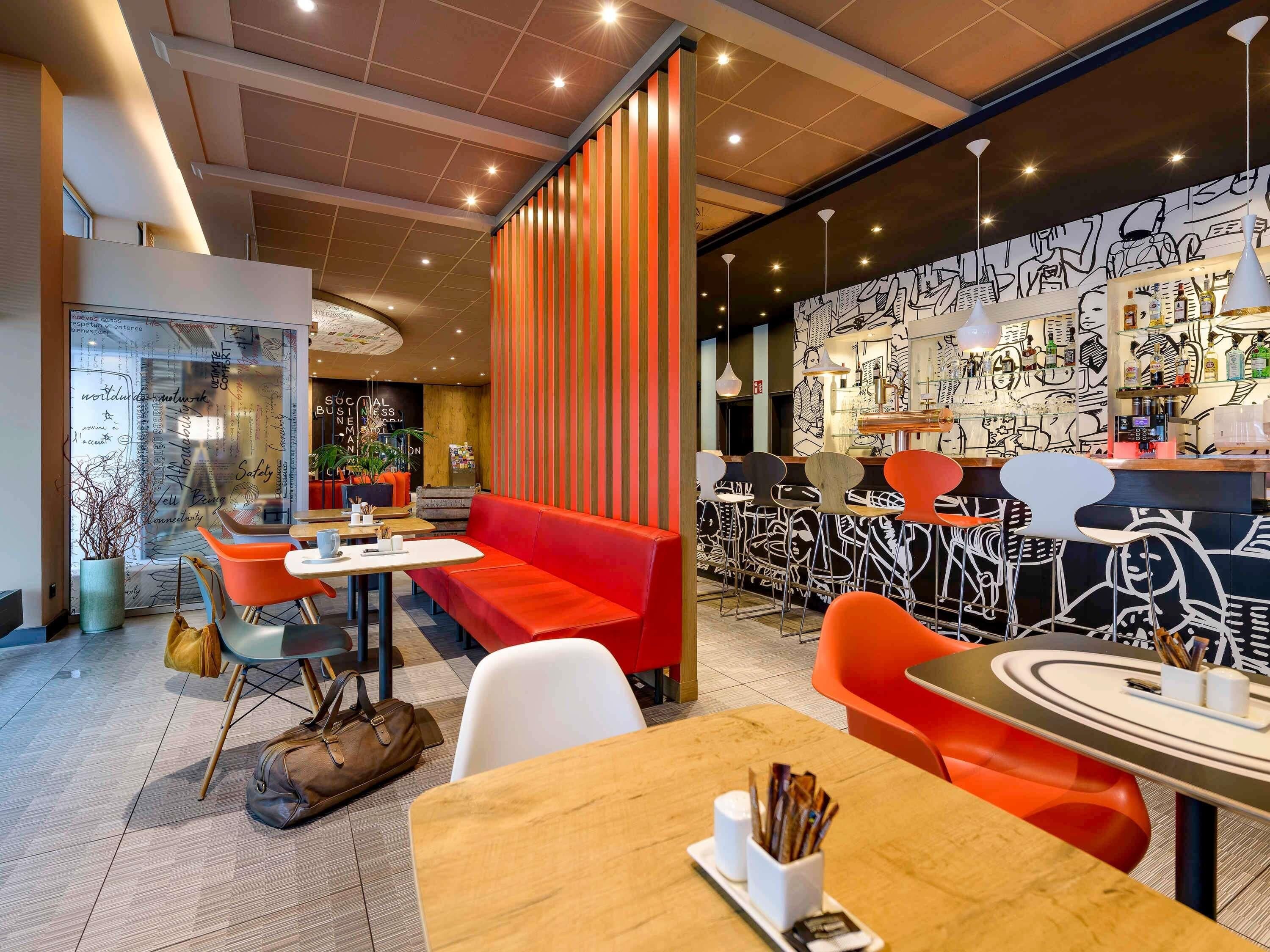 A modern restaurant with red and white decor, a bar area, and a seating arrangement including tables and chairs.