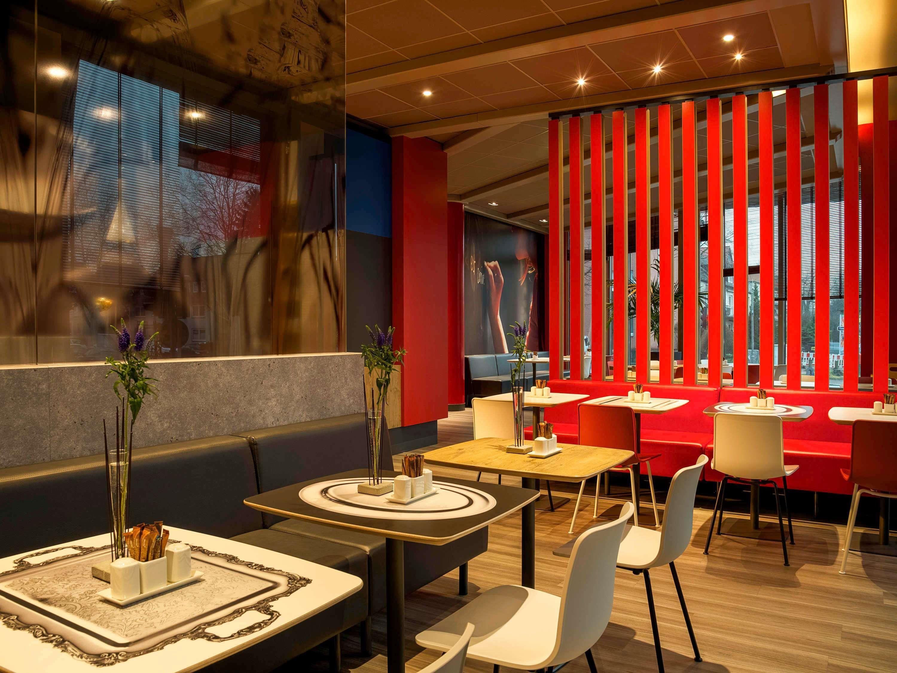 Interior moderno de restaurante con cabinas, mesas y un separador rojo.
