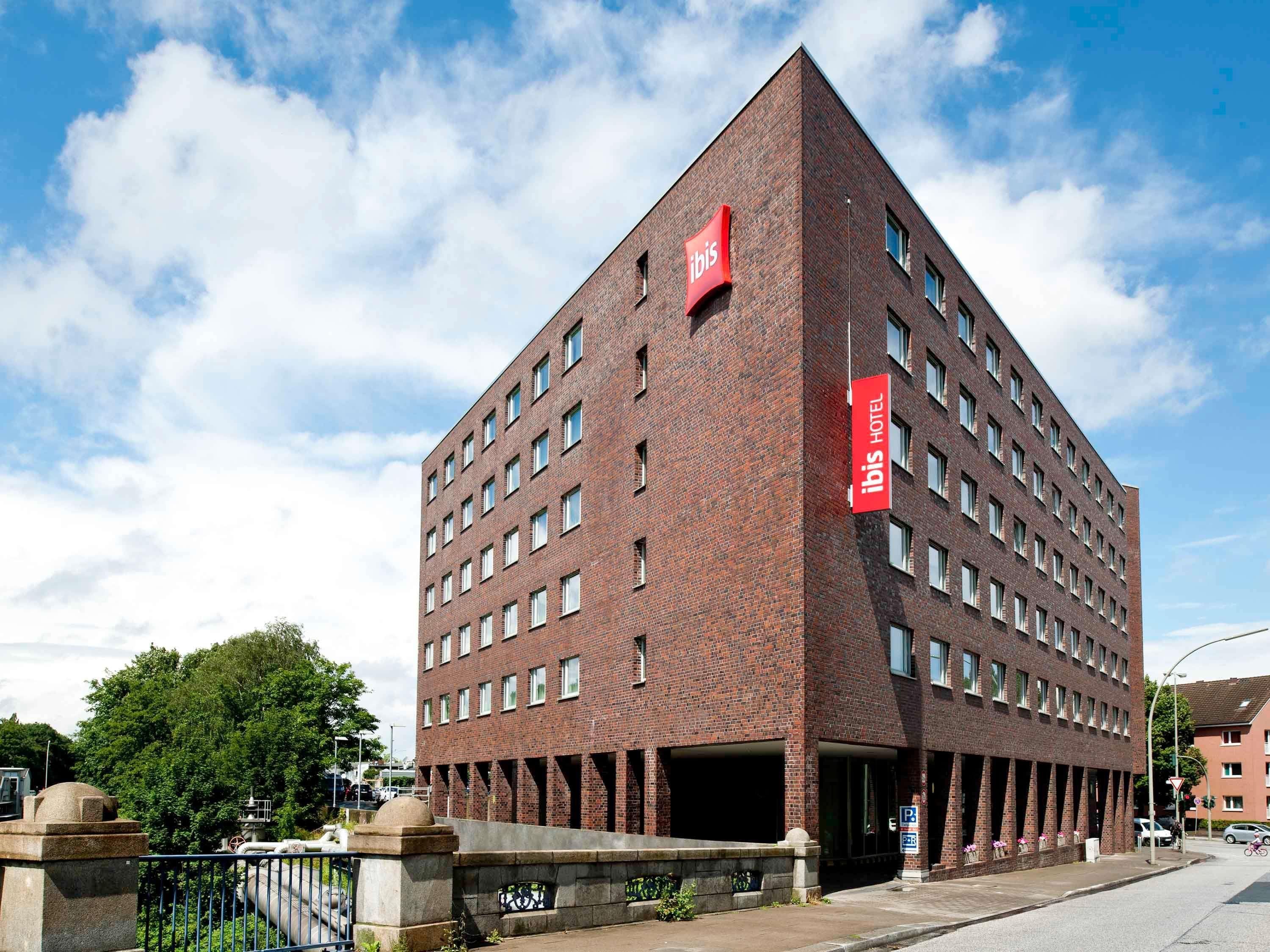 Un hotel de ladrillo rojo con múltiples ventanas y un llamativo letrero de 'ibis'.