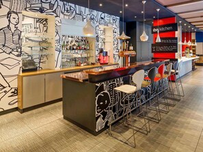 A modern bar area with a counter, stools, and a wall with abstract art. - ibis Hamburg Alsterring (Hamburg)