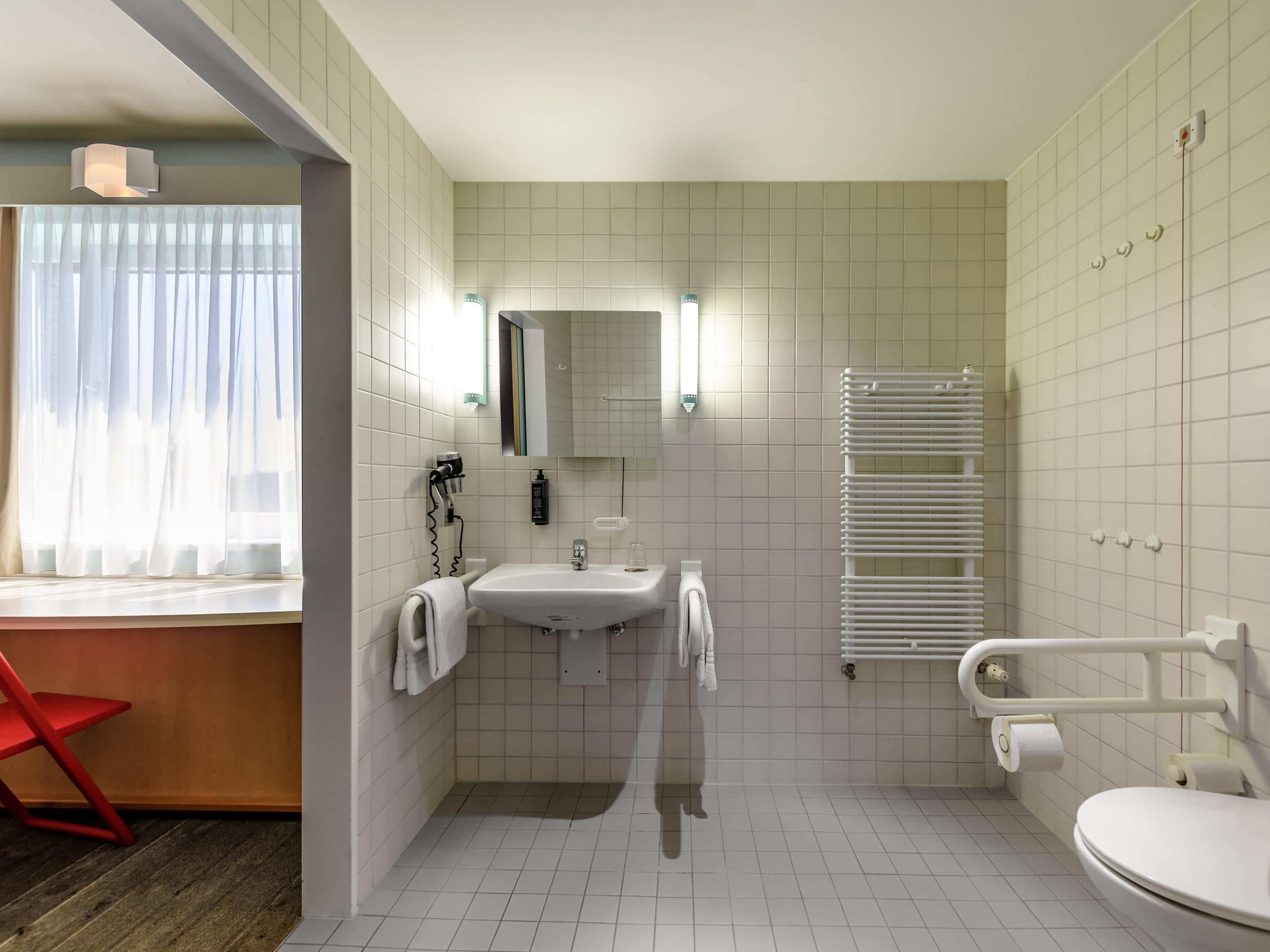 Ein modernes Badezimmer mit Waschbecken, Spiegel, Handtuchhalter, Toilette und einer Dusche mit weißem Handtuchwärmer.