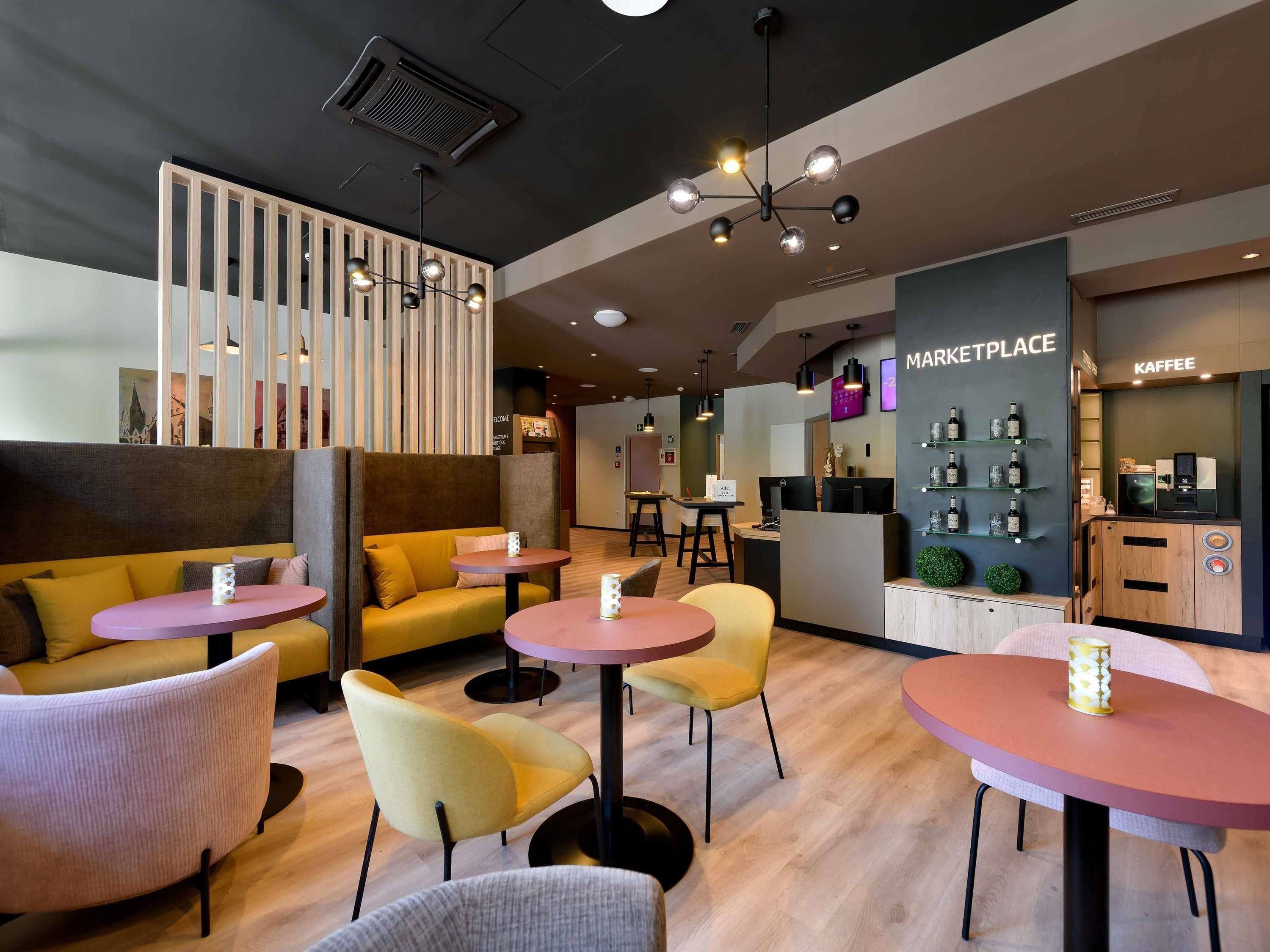 A modern lounge area with seating and a kitchenette.