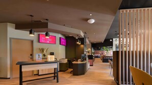 A modern reception area with a wooden desk, a key box, and a reception counter. - ibis Paderborn City (Paderborn)
