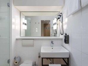 A modern bathroom with a white sink, a mirror, a towel rack, and a toilet. - ibis Paderborn City (Paderborn)