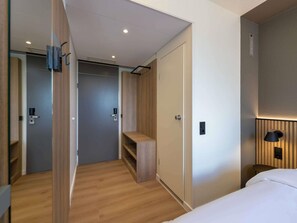 A modern hotel room with a wooden floor, a bed, a desk, and a wardrobe. - ibis Paderborn City (Paderborn)