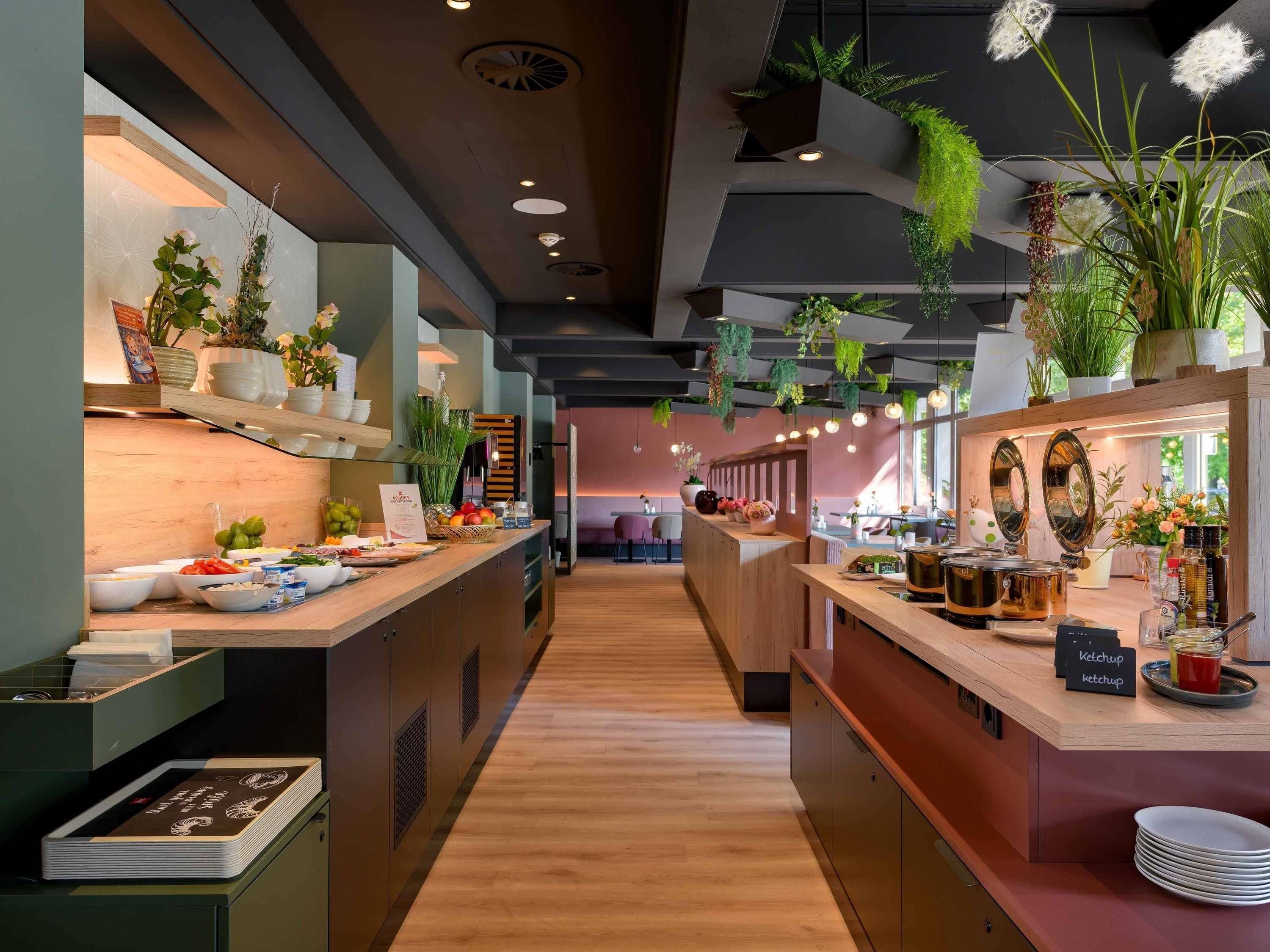 A modern hotel lobby with a central reception desk, wooden flooring, and decorative plants.