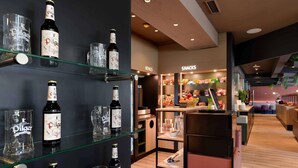A bar area with shelves displaying bottles and glasses, a snack counter, and a seating area. - ibis Paderborn City (Paderborn)
