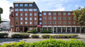 A hotel with a modern brick facade, multiple windows, and a clear sky. - ibis Paderborn City (Paderborn)