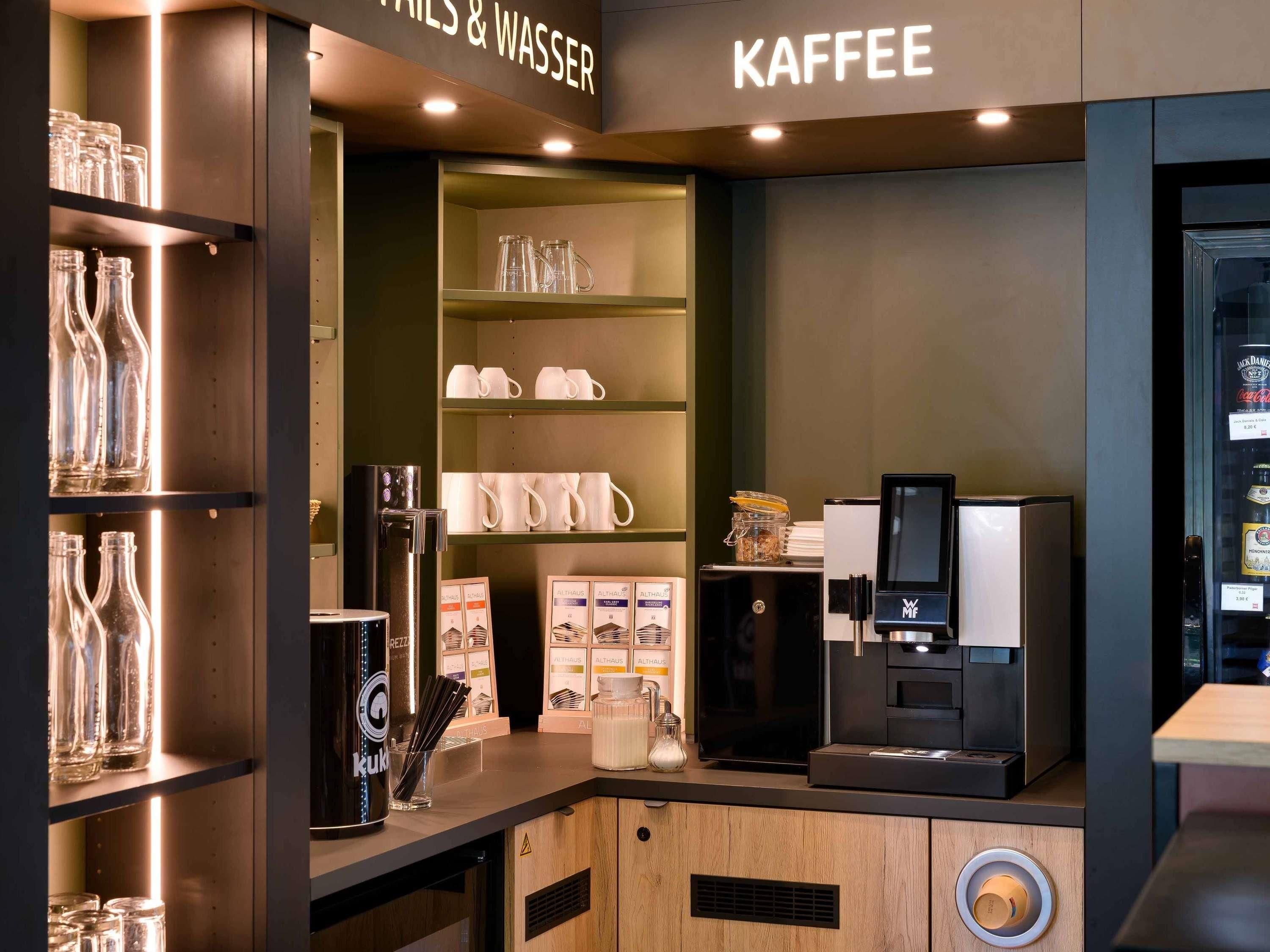 A coffee station with a coffee machine, mugs, and glassware.