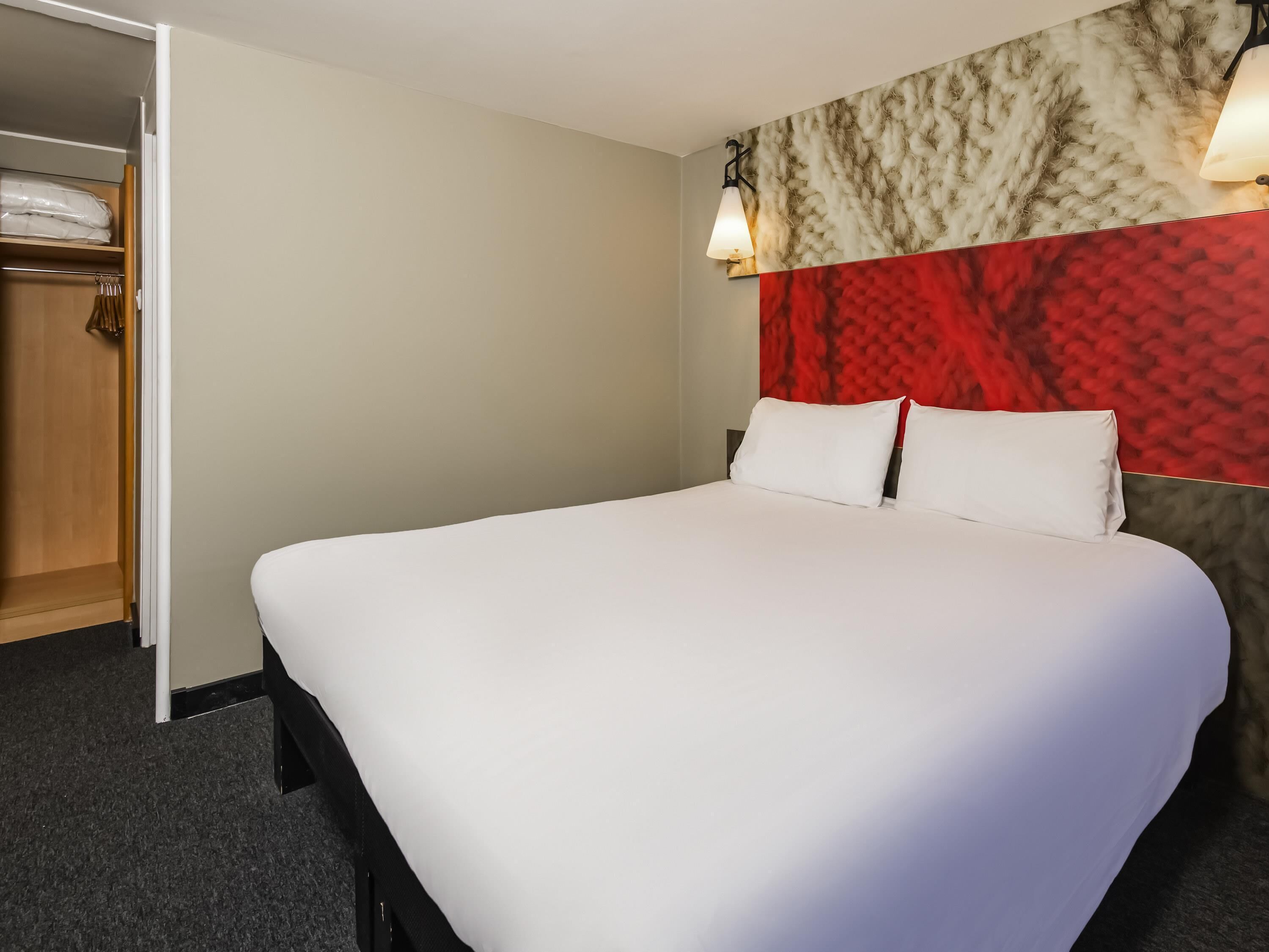 A neatly made bed with white linens in a hotel room.