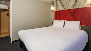 Una cama bien hecha con sábanas blancas en una habitación de hotel.