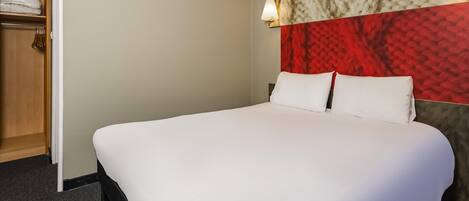 En välordnad säng med vita sängkläder i ett hotellrum.