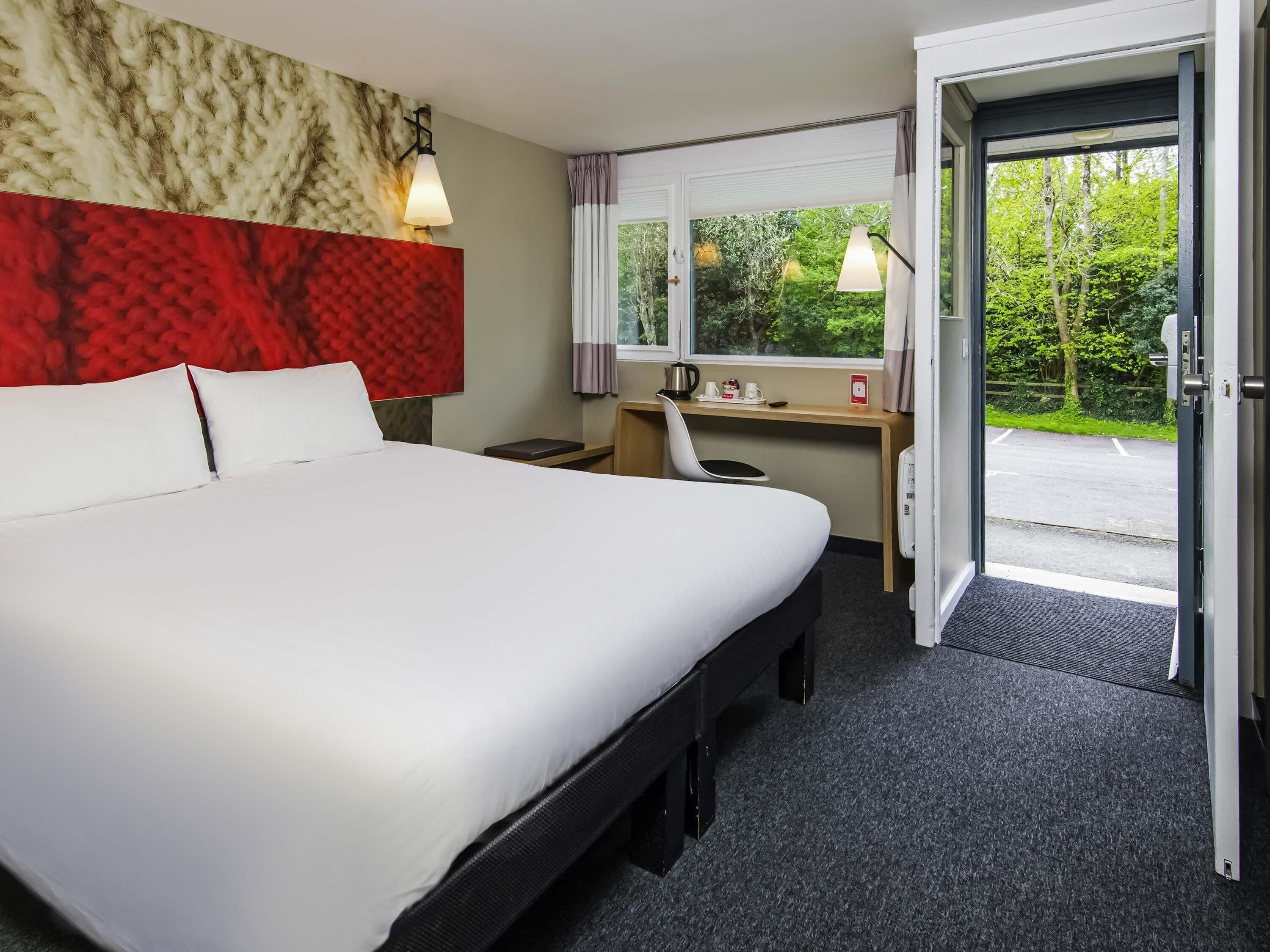 Una habitación de hotel con cama, escritorio, silla y vistas al exterior.