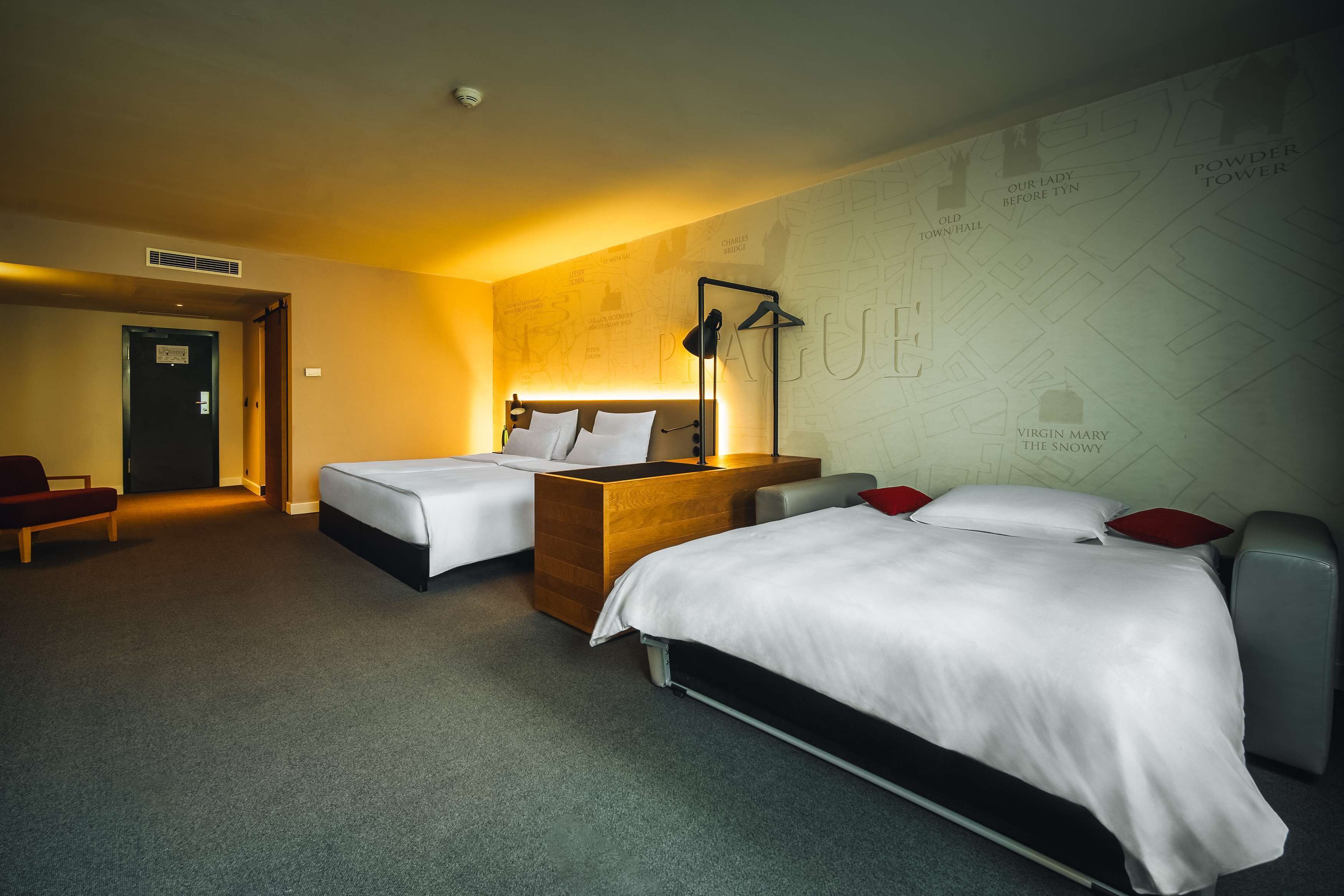 Ein Hotelzimmer mit zwei Betten, einer Holzkommode, einem Schreibtisch und einer Wand voller Karten.