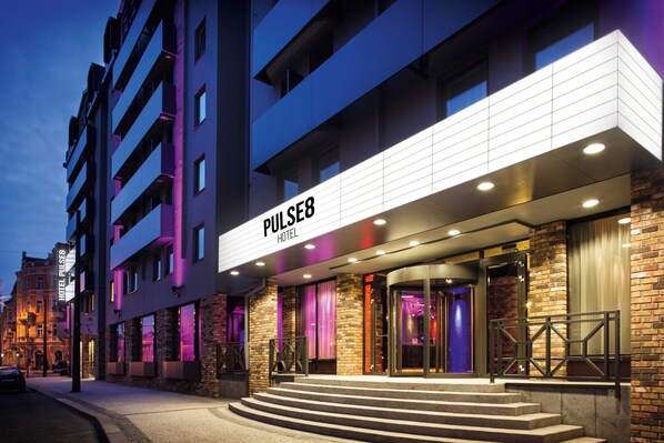 Una entrada de hotel moderna con un letrero llamativo que dice 'PULSE8 HOTEL'.