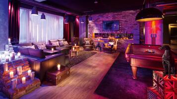 A cozy lounge area with a pool table, comfortable seating, and a bar.