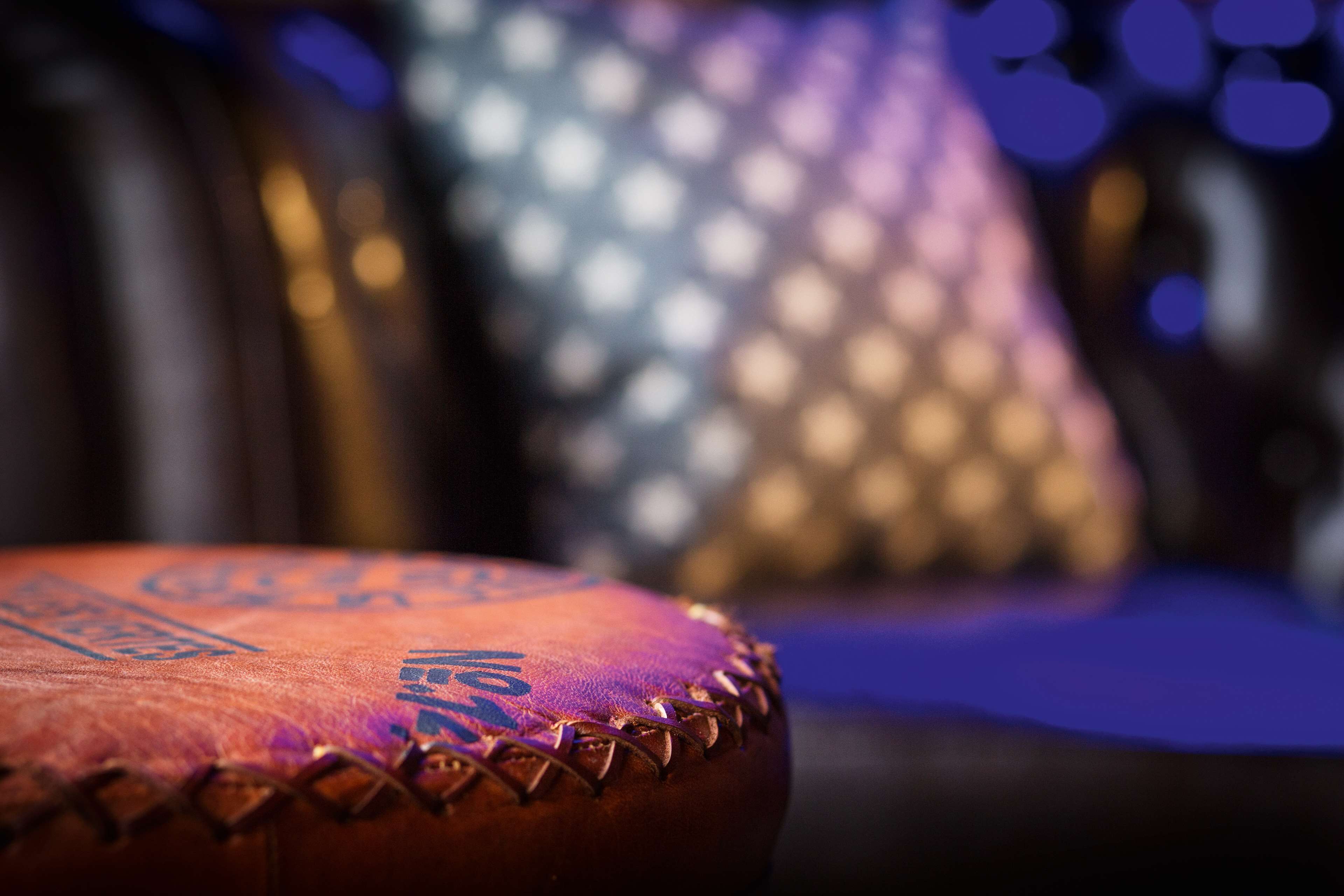 Un primo piano di un pallone da calcio in pelle con cuciture e scritte, su uno sfondo sfocato con effetto bokeh.