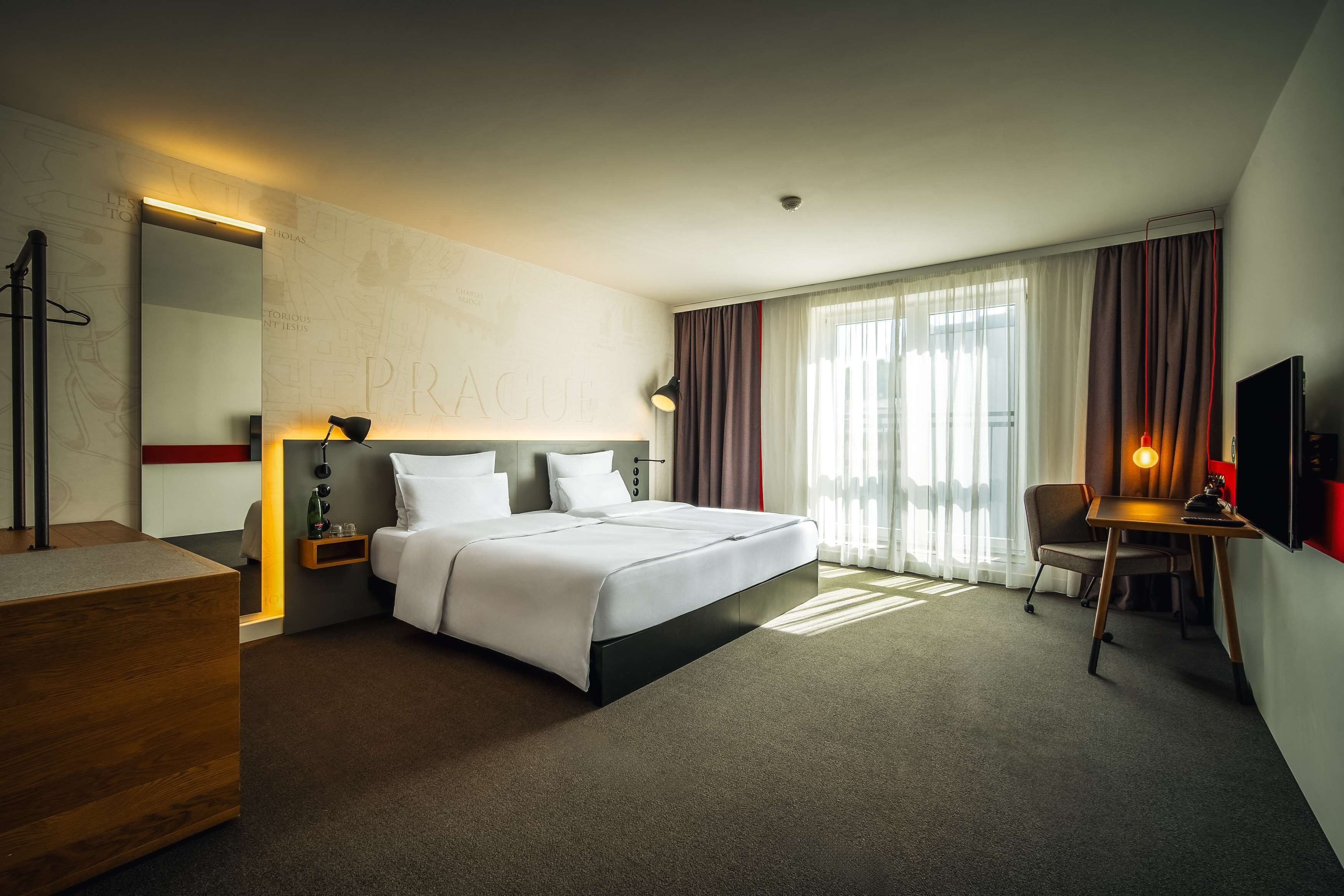 Una camera d'hotel moderna con un letto grande, comodini, una scrivania e una televisione.