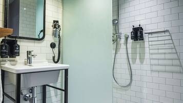 Un baño moderno con lavamanos, espejo y ducha blancos.