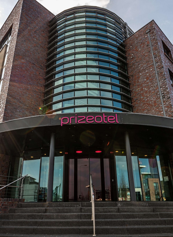 A modern building with a curved glass facade and a sign reading "prizeotel."
