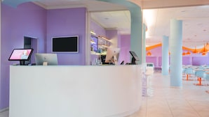 A reception area with a curved white desk, a flat-screen TV, and a computer monitor.