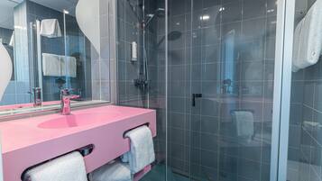 Ein modernes Badezimmer mit einem rosa Waschbecken, einer Glasdusche und einem großen Spiegel.