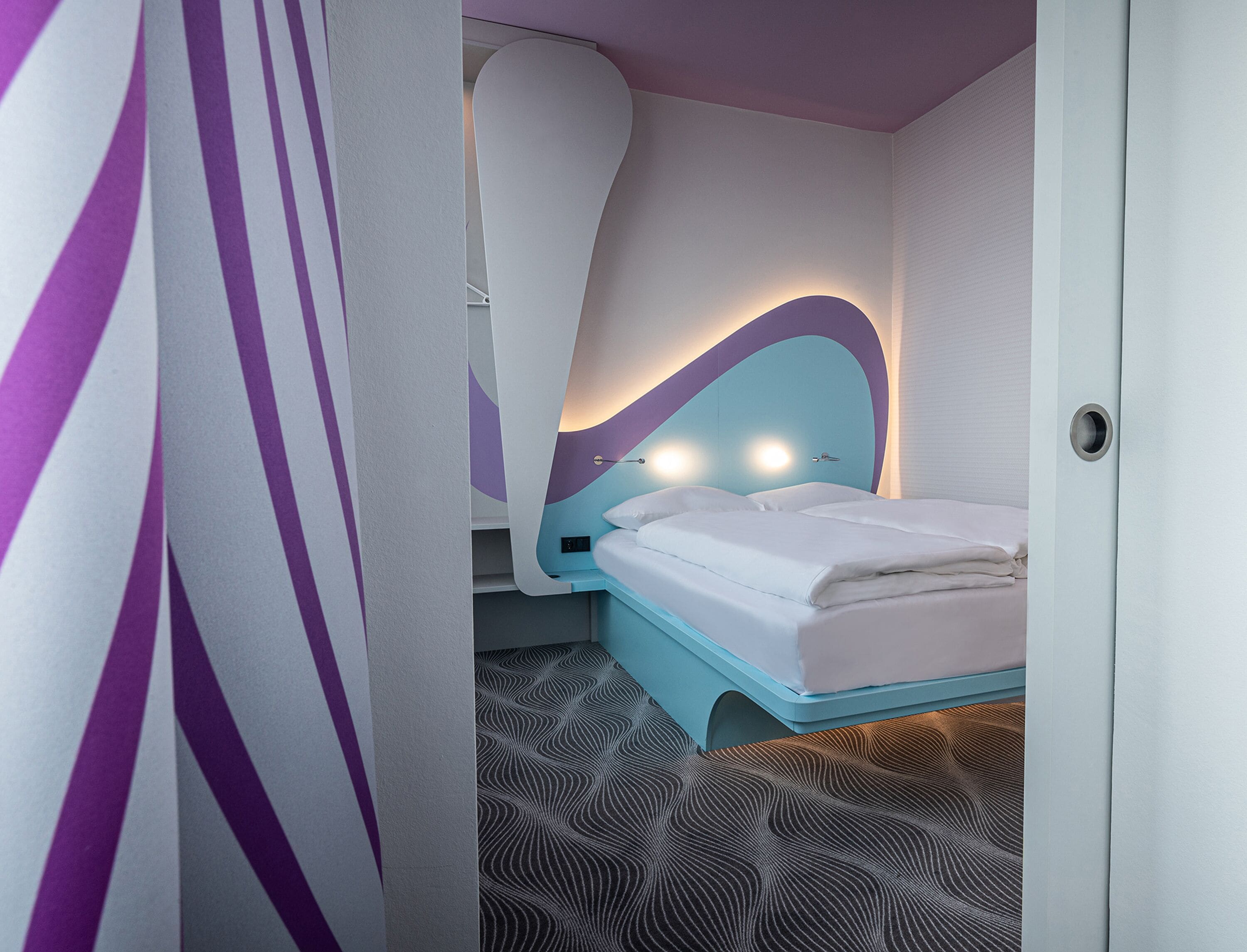 Un dormitorio moderno con un llamativo cabecero curvo, una cama bien hecha y un suelo estampado.
