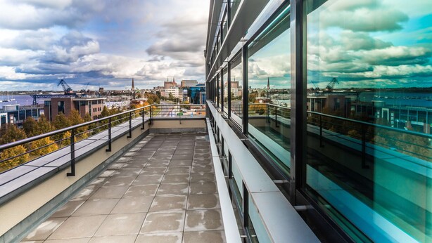 A modern building with large windows overlooking a cityscape and a body of water.