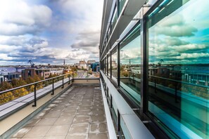 A modern building with large windows overlooking a cityscape and a body of water. - Prize by Radisson, Rostock City (Rostock)