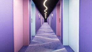 A long, narrow hallway with a wavy light fixture on the ceiling and a patterned carpet.