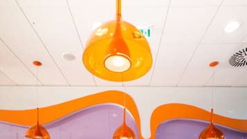 Een modern interieur met oranje en blauwe zitplaatsen, hanglampen en een gestreept plafond.