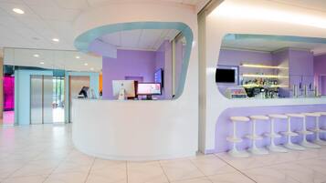 A reception area with a curved counter, a computer, and a bar with stools.