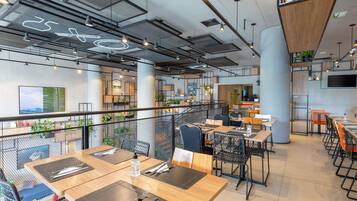 A modern dining area with tables, chairs, and a mezzanine level with plants.