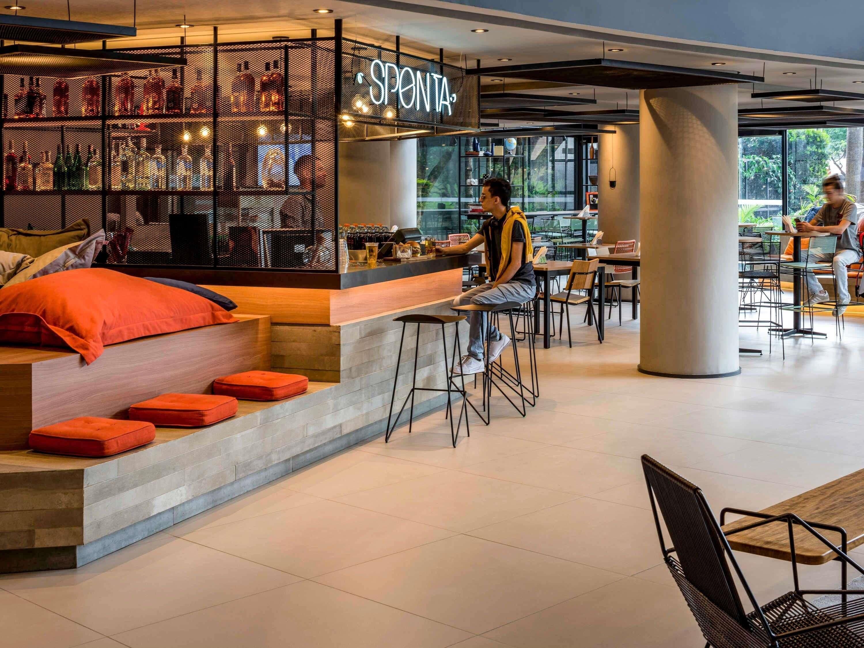 Zona de bar moderna con un letrero de neón, asientos y una barra.