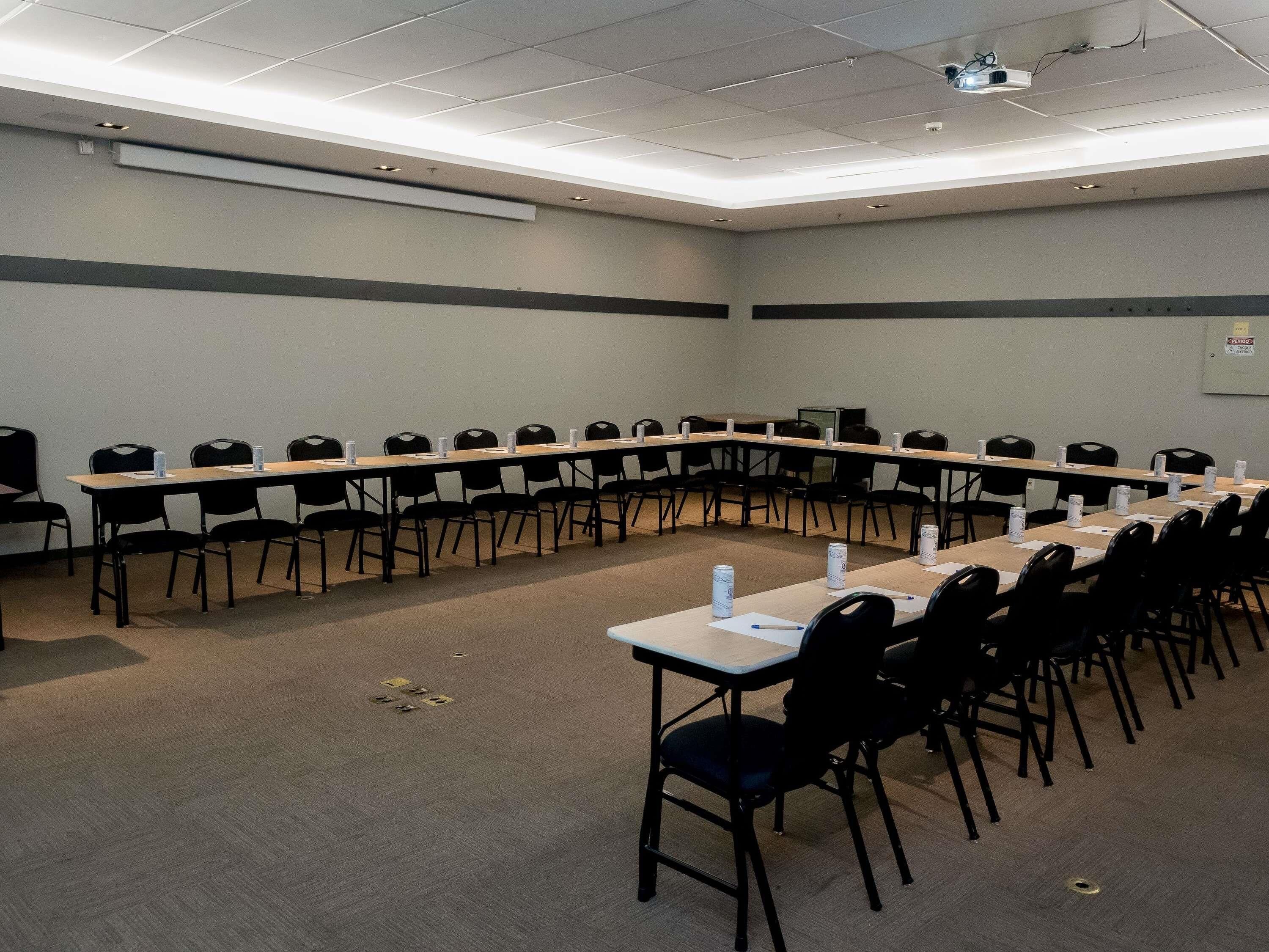 Una sala de conferències amb una taula llarga, cadires i un projector al sostre.
