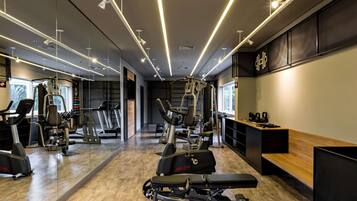 A gym with exercise equipment, mirrors, and a wooden bench.