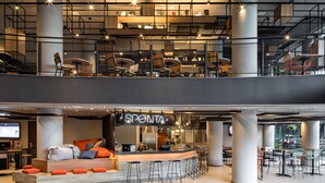 Een modern interieur met een bar, zitplaatsen en een zichtbaar restaurant genaamd SPONTA.